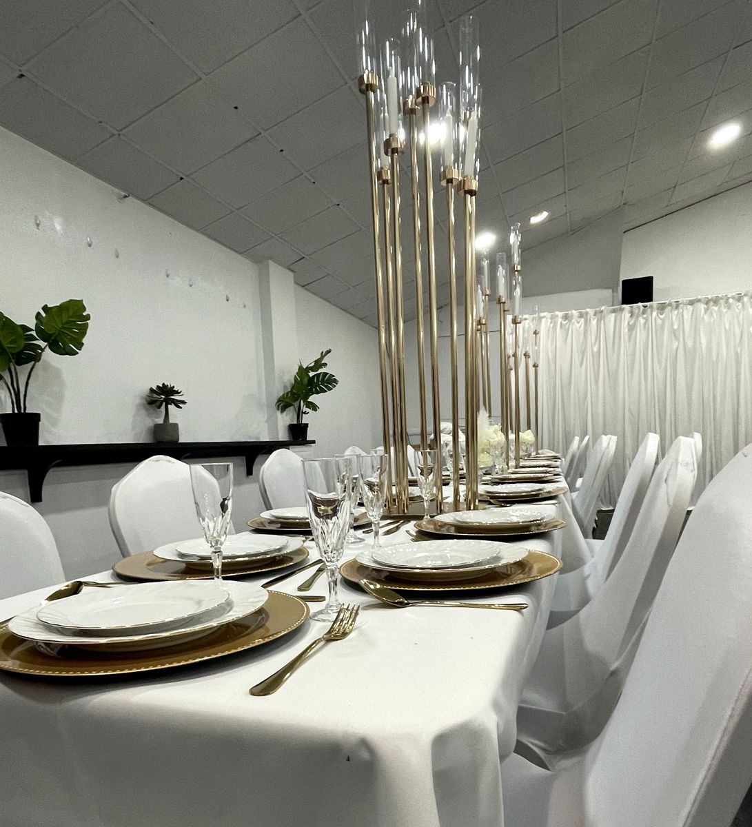 Long table set with gold chargers, gold cutlery and tall gold candelabra